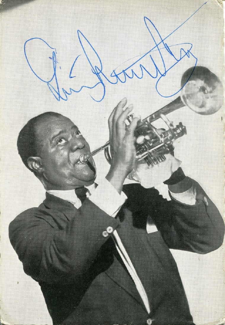 ARMSTRONG LOUIS: (1901-1971): ARMSTRONG LOUIS: (1901-1971) American jazz trumpeter and vocalist. Vintage signed 4 x 5.75 postcard photograph of Satchmo in a half-length pose playing his trumpet. Signed in blue ink with his name