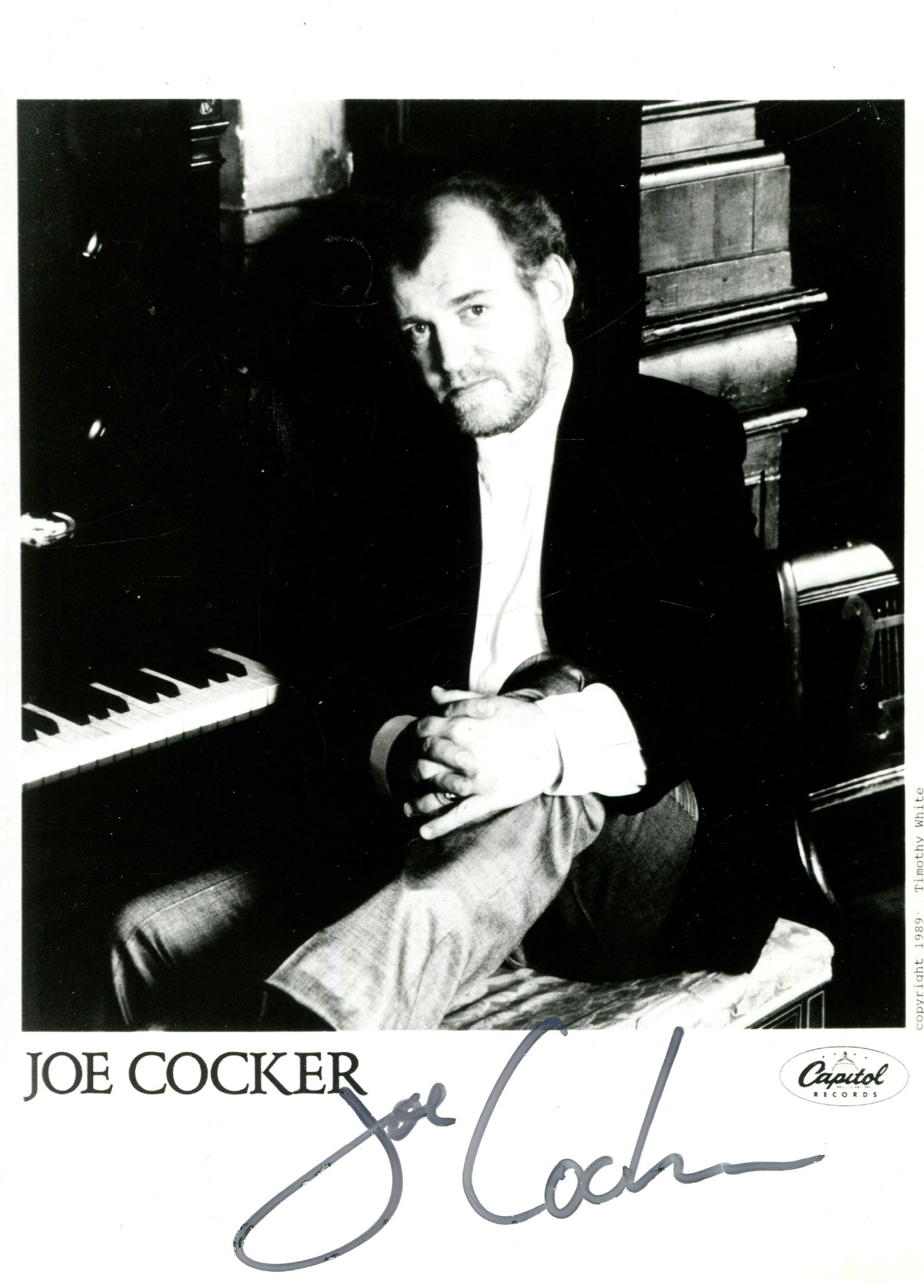 COCKER JOE: (1944-2014): COCKER JOE: (1944-2014) English Singer. Signed 5 x 7 photograph of Cocker seated in a half-length pose with a piano behind him. Signed in bold black ink with his name alone to the lower white border