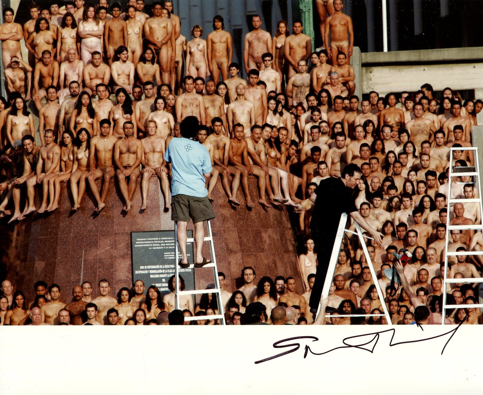 TUNICK SPENCER: (1967- ): TUNICK SPENCER: (1967- ) American photographer. Signed colour 10 x 8 photograph of Tunick standing in a full-length pose on a tall stepladder as he prepares one of his signature large-scale nude