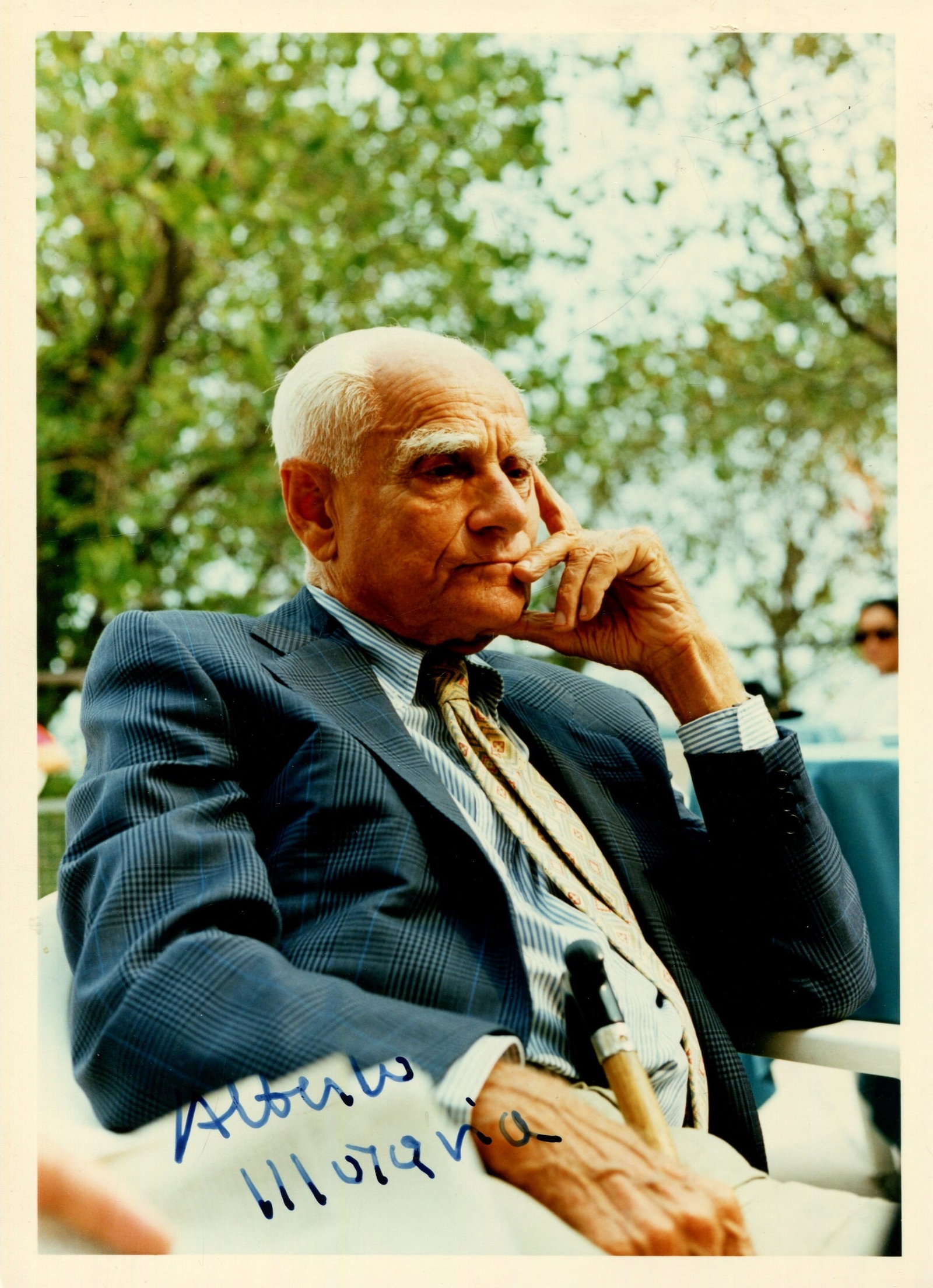 MORAVIA ALBERTO: (1907-1990): MORAVIA ALBERTO: (1907-1990) Italian novelist and journalist. A good and unusual signed colour 5 x 7 photograph by Moravia, the image showing the Italian writer seated outdoors in a half-length