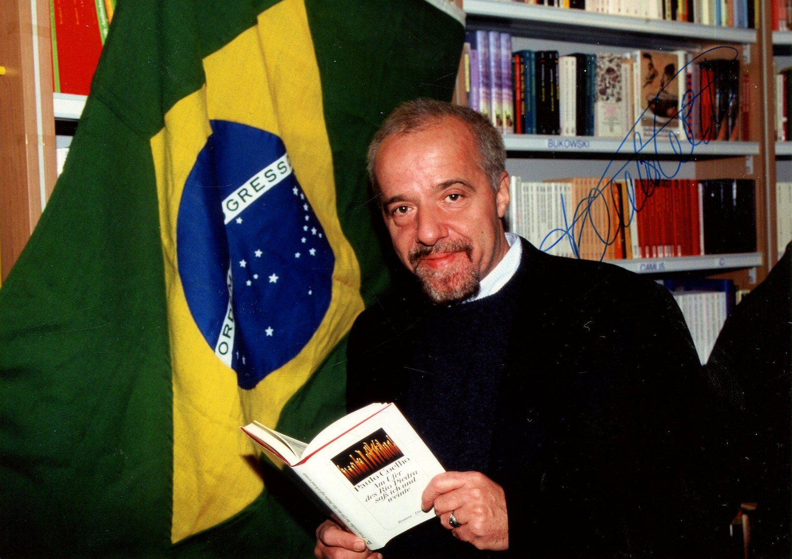 COELHO PAULO: (1947- ): COELHO PAULO: (1947- ) Brazilian Novelist. Best known for his international best-seller The Alchemist (1988). Signed colour 7 x 5 photograph by Coelho, the image showing the awarded novelist standing