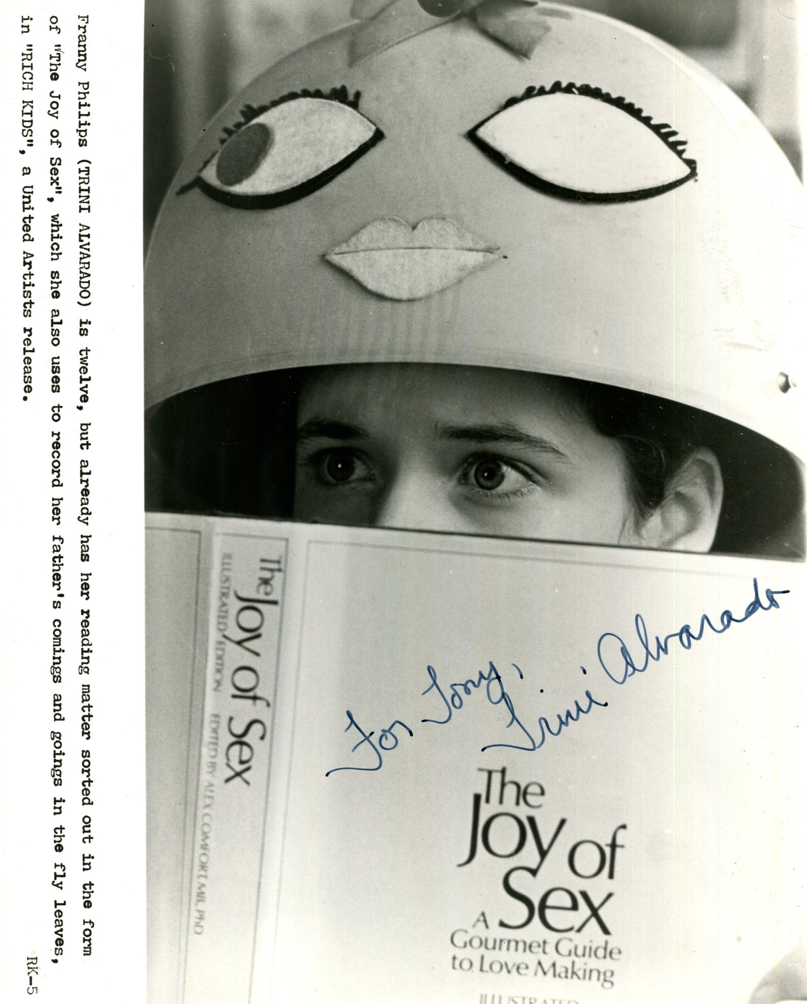 ALVARADO TRINI: (1967- ): ALVARADO TRINI: (1967- ) American actress. Signed and inscribed 8 x 10 photograph of the actress in costume as Franny Phillips, peering over the top of a copy of The Joy of Sex, from the American