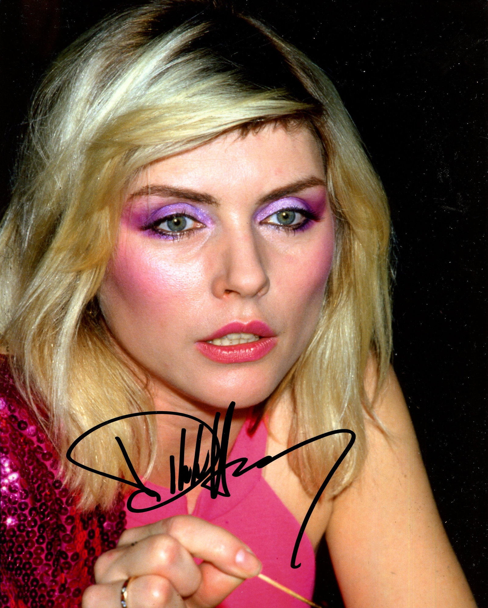 HARRY DEBBIE: (1945- ): HARRY DEBBIE: (1945- ) American singer and songwriter, lead vocalist of the rock band Blondie. Signed colour 8 x 10 photograph of Harry in a close-up head and shoulders pose holding a cocktail stick