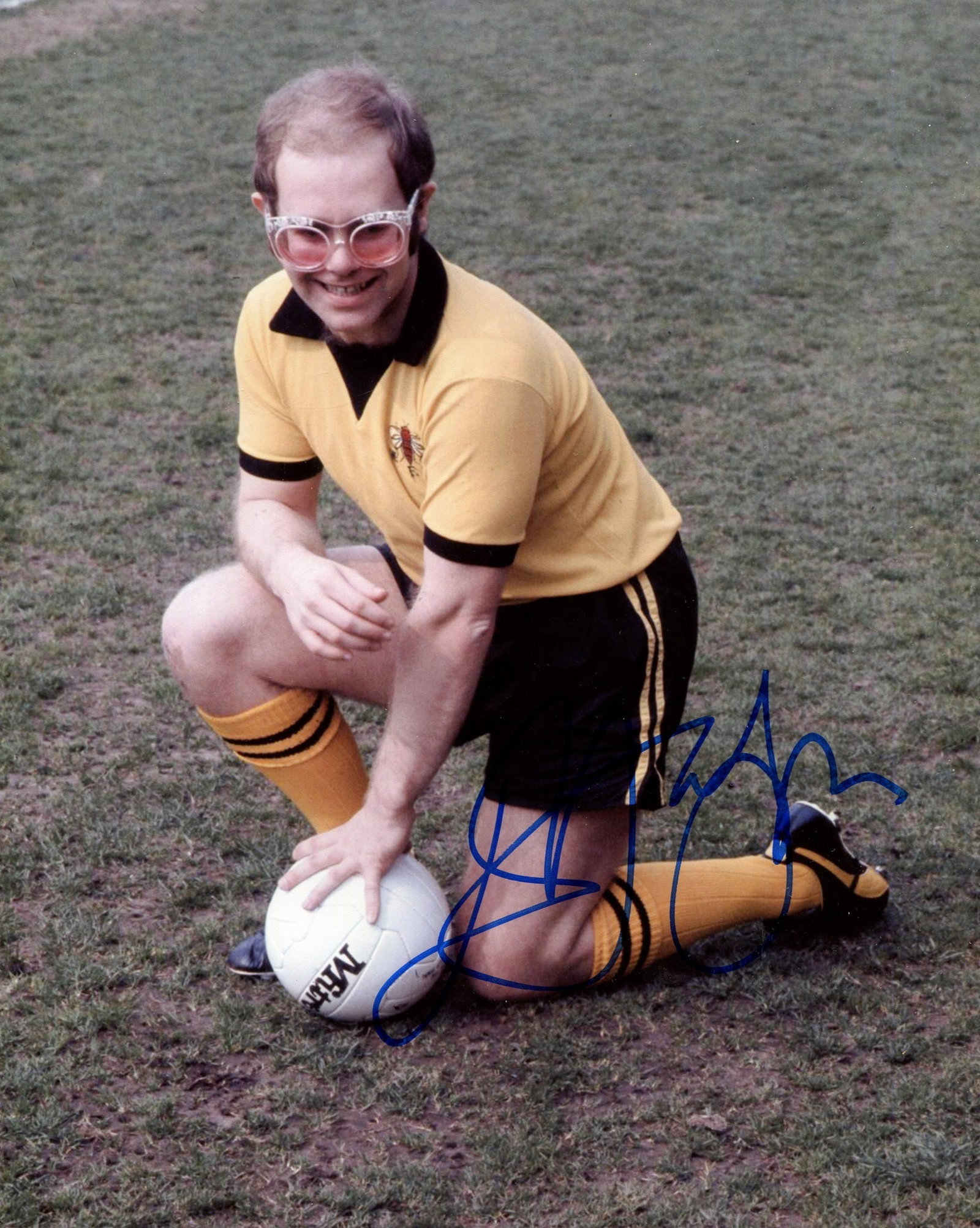 JOHN ELTON: (1947- ): JOHN ELTON: (1947- ) British singer and pianist, Academy Award winner. Signed colour 8 x 10 photograph of John genuflecting in a full-length pose, wearing a Watford Football Club strip and trademark