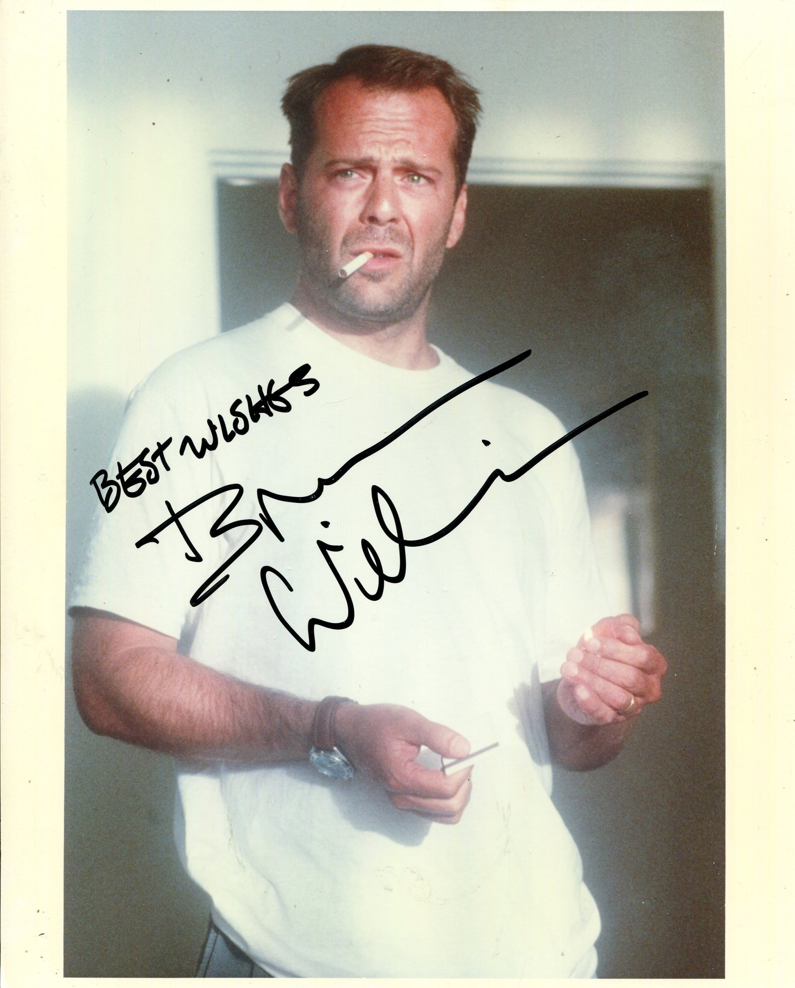WILLIS BRUCE: (1955- ): WILLIS BRUCE: (1955- ) American actor. Signed colour 8 x 10 photograph of Willis standing in a half-length pose as he prepares to light the cigarette in his mouth from a matchbook. Signed in bold