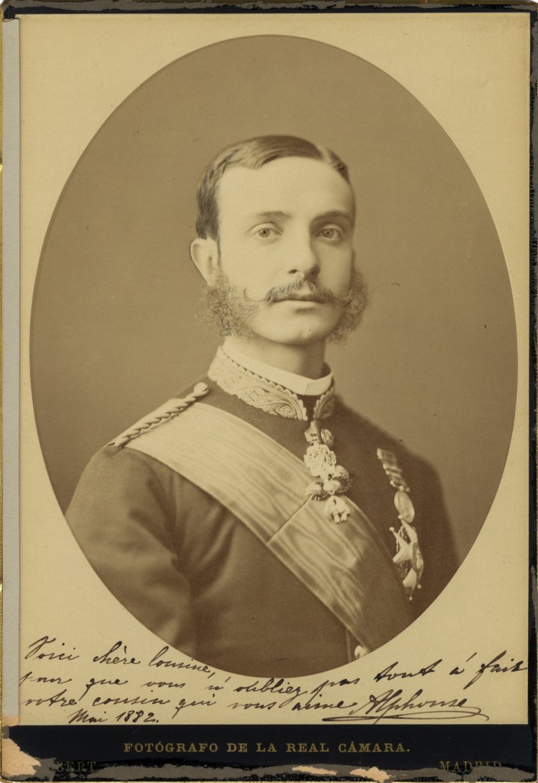 ALFONSO XII: (1857-1885) King of Spain 1874-85. A good: ALFONSO XII: (1857-1885) King of Spain 1874-85. A good vintage signed and inscribed sepia Imperial cabinet photograph (7 x 10), the oval image depicting the young King in a head and shoulders pose wea