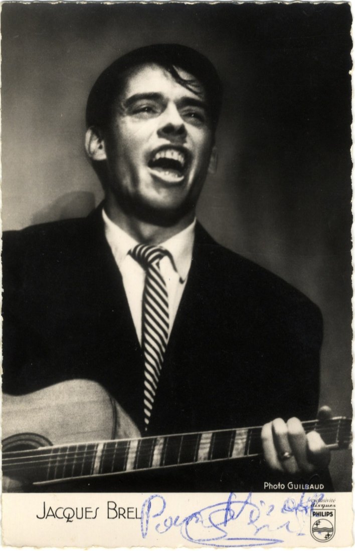 BREL JACQUES: (1929- 1978) Belgian Singer & Songwriter.: BREL JACQUES: (1929- 1978) Belgian Singer & Songwriter. Vintage signed and inscribed postcard photograph of Brel in a half length pose playing his guitar. The promotional Philips image is by Guilbaud.