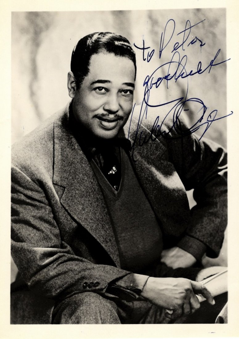 ELLINGTON DUKE: (1899-1974) American Jazz Pianist.: ELLINGTON DUKE: (1899-1974) American Jazz Pianist. Vintage signed 5 x 7 photograph of Ellington seated in a three quarter length pose. Signed in bold blue fountain pen ink across a light area of the i
