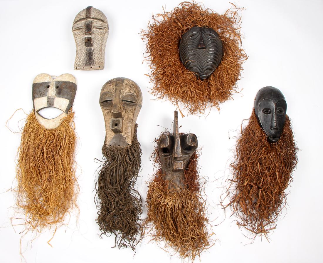 Six African Masks: Six African Masks. Carved wood, pigment and raffia. Including Lega, Holo, Kifwebe examples. Largest: 14.5'' x 8'' x 6.5'' (37 x 20 x 17 cm); 30"L (76 cm) including beard.