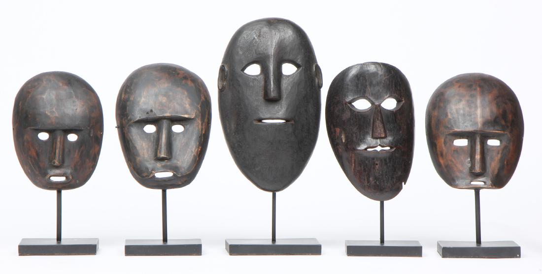 5 Carved Indonesian Tribal Style Masks: 5 Carved Wood Masks. Largest object: 11.5'' x 6.75'' x 2.5'' (29 x 17 x 6 cm). Height on stand: 15" (38 cm).