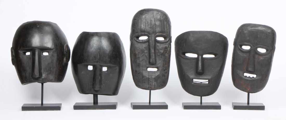 5 Carved Indonesian Tribal Style Masks: 5 Carved Masks. Largest object: 13.25'' x 6.75'' x 2.75'' (34 x 17 x 7 cm). Height on stand: 15.75" (40 cm).