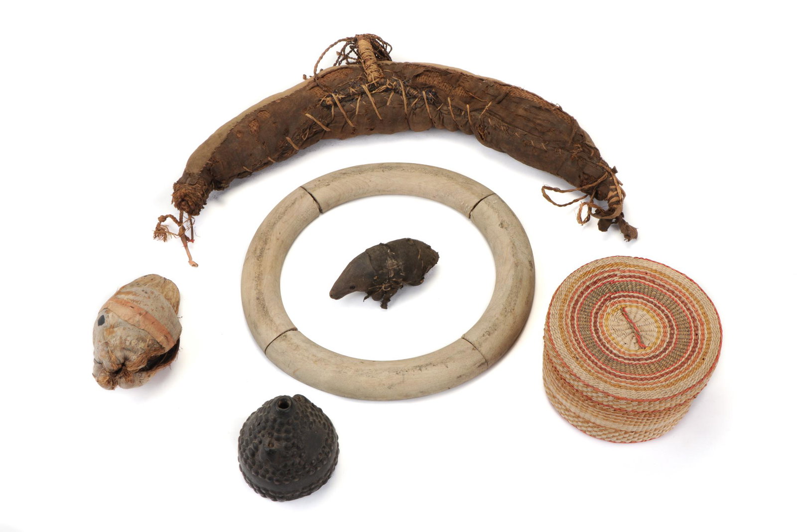 Assorted African Items: Assorted African Items. Including a metal-studded conical wood flask, a yonic seed pod fetish, woven covered basket, circular wooden object, zoomorphic object, crescent form object. Cloth, seeds, wood