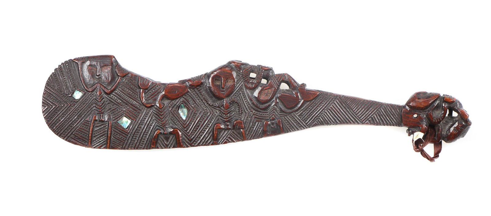 Maori Carved Wood Wahaika Ceremonial Club: Maori Carved Wood Wahaika Ceremonial Club. The curved blade with mother-of-pearl inlay and deeply carved linear and figural designs, with a tiki figure on the inside, the handle end in the form of a s
