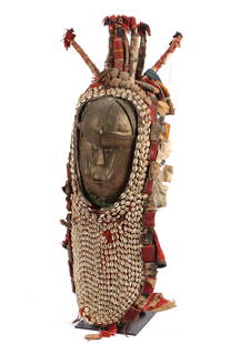 African Temne Peoples Brass Mask Headdress, Sierra: African Temne Peoples Brass Mask Headdress, Sierra Leone on stand. Brass mask with cloth and cowrey shell headdress. Size: 40'' x 12'' x 12'' (102 x 30 x 30 cm). Collection of Allan Stone, New York.