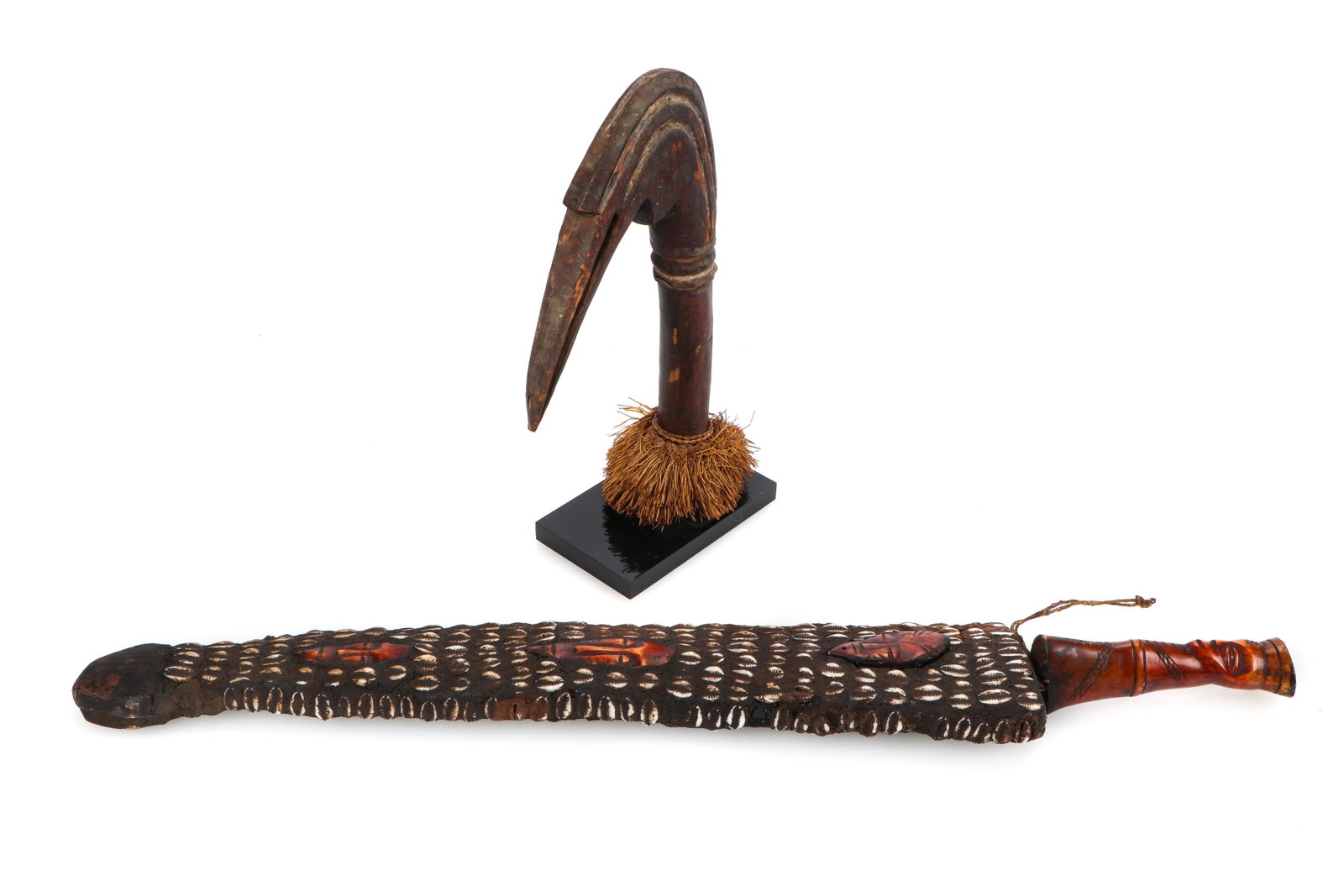 African Baga Bird Staff and Kuba Sword: African Baga Bird Staff and Kuba Sword. The bird staff head with raffia, the sword with bone handle, sheath decorated with cowrey shells and inset bone masks. Sizes: 1) 12'' x 7'' x 1.25'' (30 x 18 x 