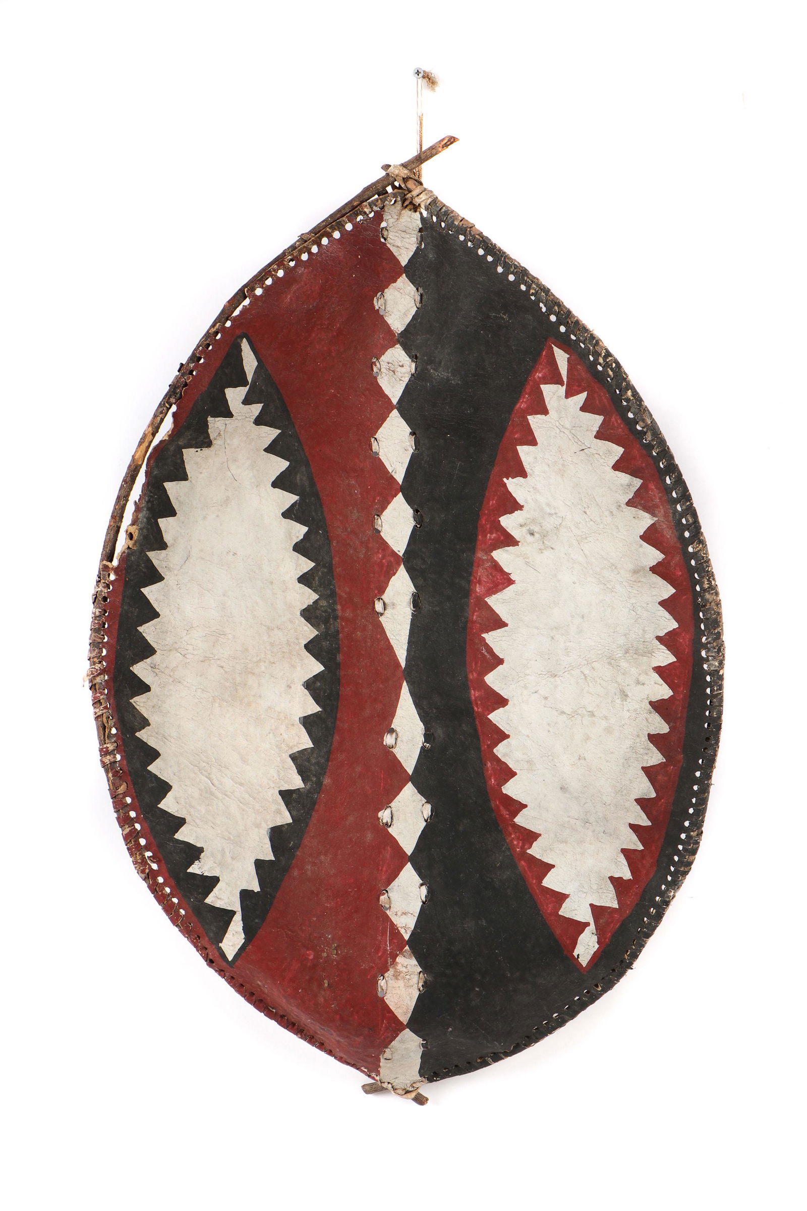 Old African Maasai Painted Cow Hide Shield, Kenya: Old African Maasai Painted Cow Hide Shield, Kenya. Of concave almond shape and arched wood handle grip to inside, the outside with muted red, black and white pigments in geometric designs. Shape warpe