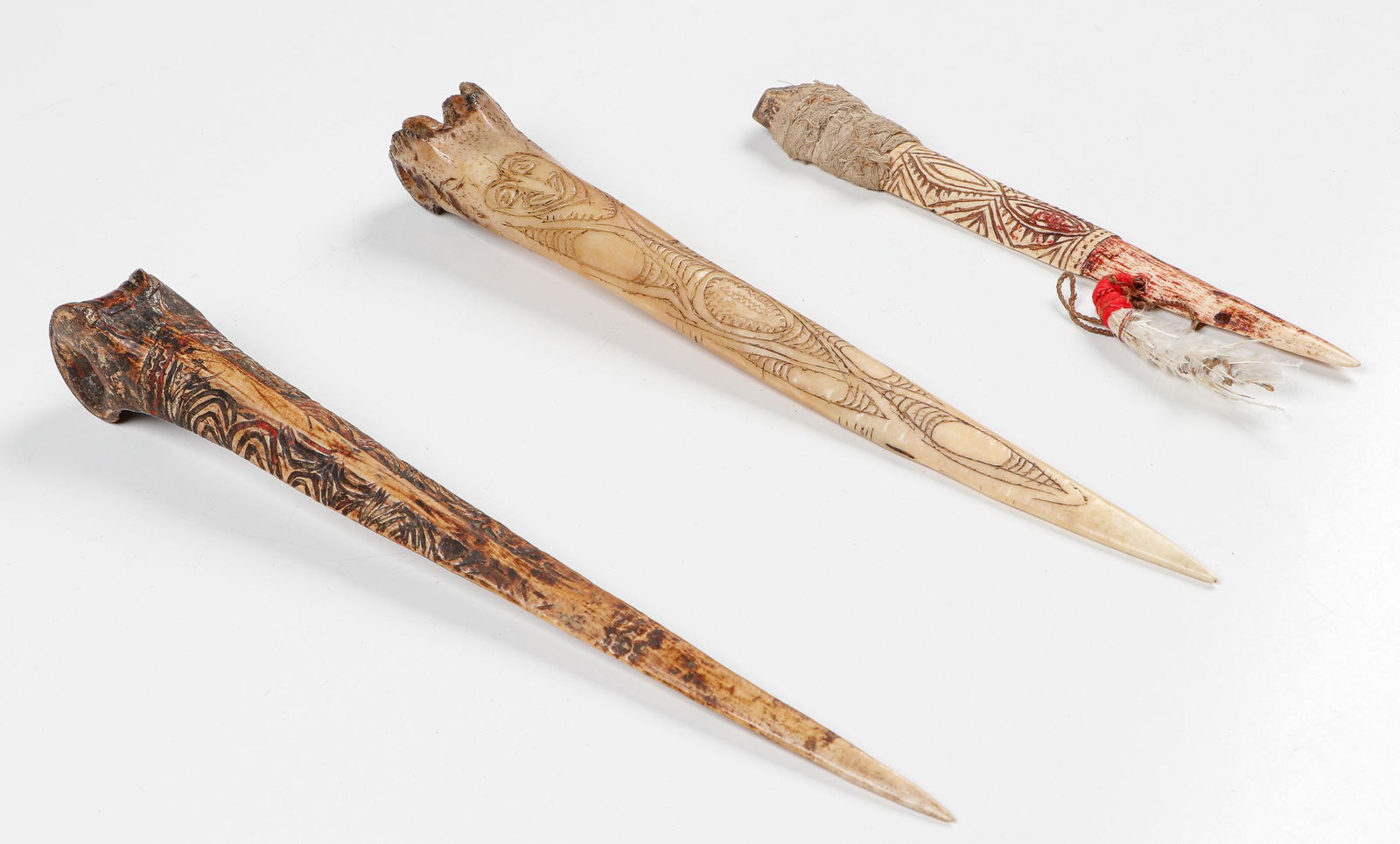 3 Carved Cassowary Bone Daggers, PNG: 3 Carved Cassowary Bone Daggers, PNG. With incised and feather decoration. Size: Ranging from: 9.5'' x 1'' x .5'' (24 x 3 x 1 cm) to 13.5'' x 1.5'' x 1.5'' (34 x 4 x 4 cm)