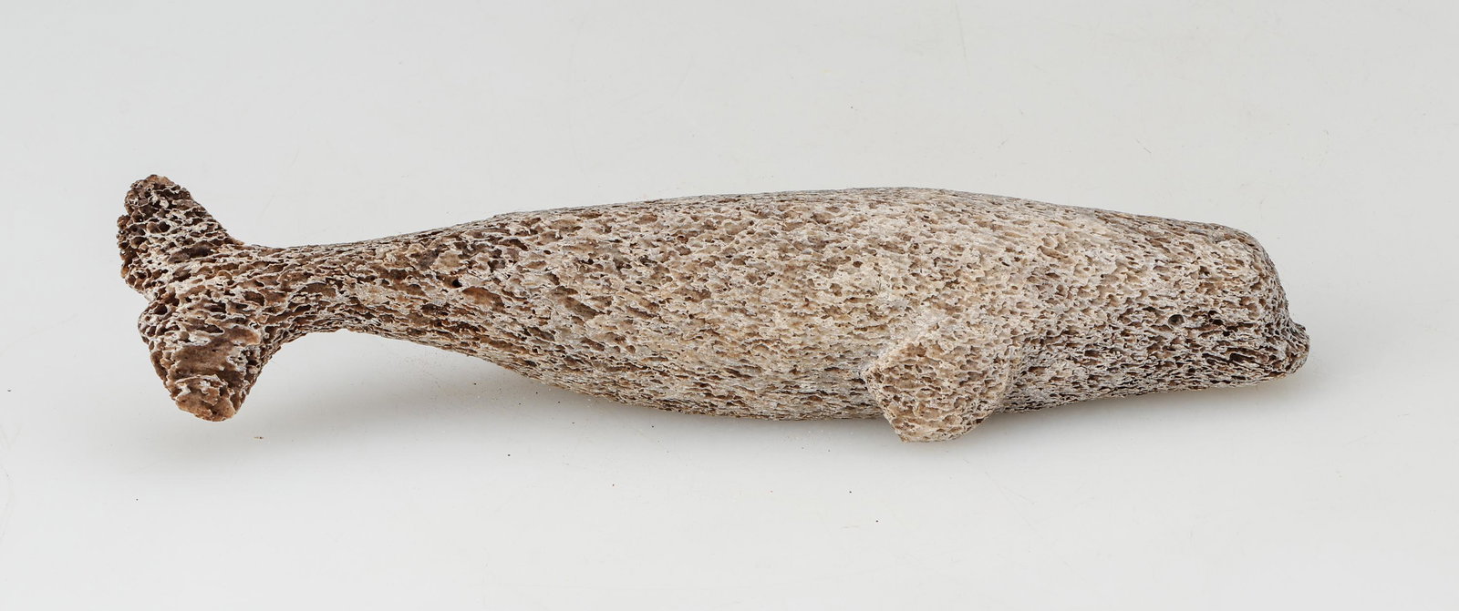 Beluga Whale Effigy, Fossilized Whale Bone: Beluga Whale Effigy, Attributed to Suqualuk Akesuk (Cape Dorset / Kinngait, b.1959 -E7-1669), Fossilized Whale Bone Carving.Size: 10.25'' x 2'' x 2.5'' (26 x 5 x 6 cm). Provenance: The Gallery of Eski