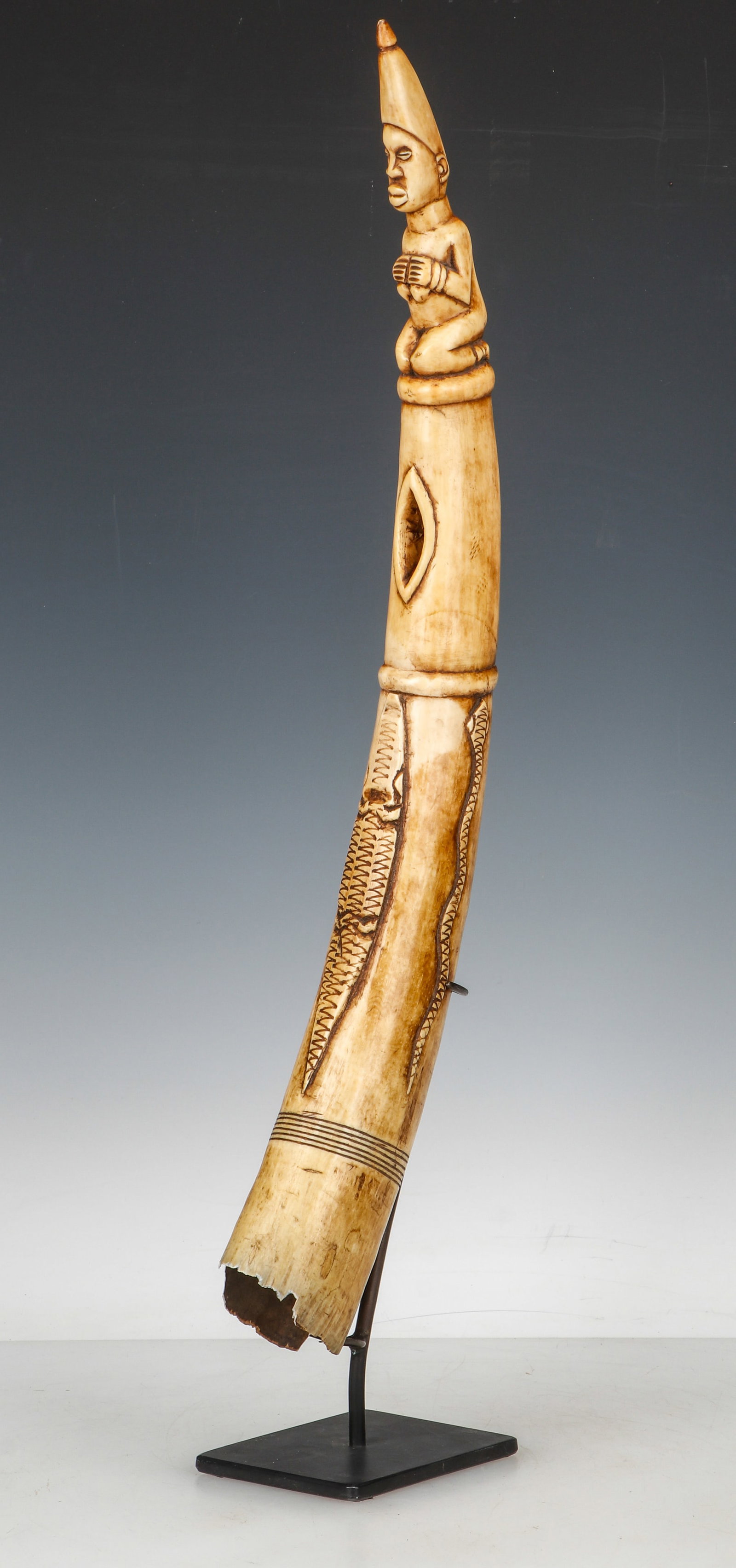 Antique African Side-Blown Trumpet Horn, Nigeria: Antique African Side-Blown Trumpet Horn, Nigeria. With a kneeling figure above the mouth hole and relief carved reptiles. On Stand. Size: Length 20" (51 cm).