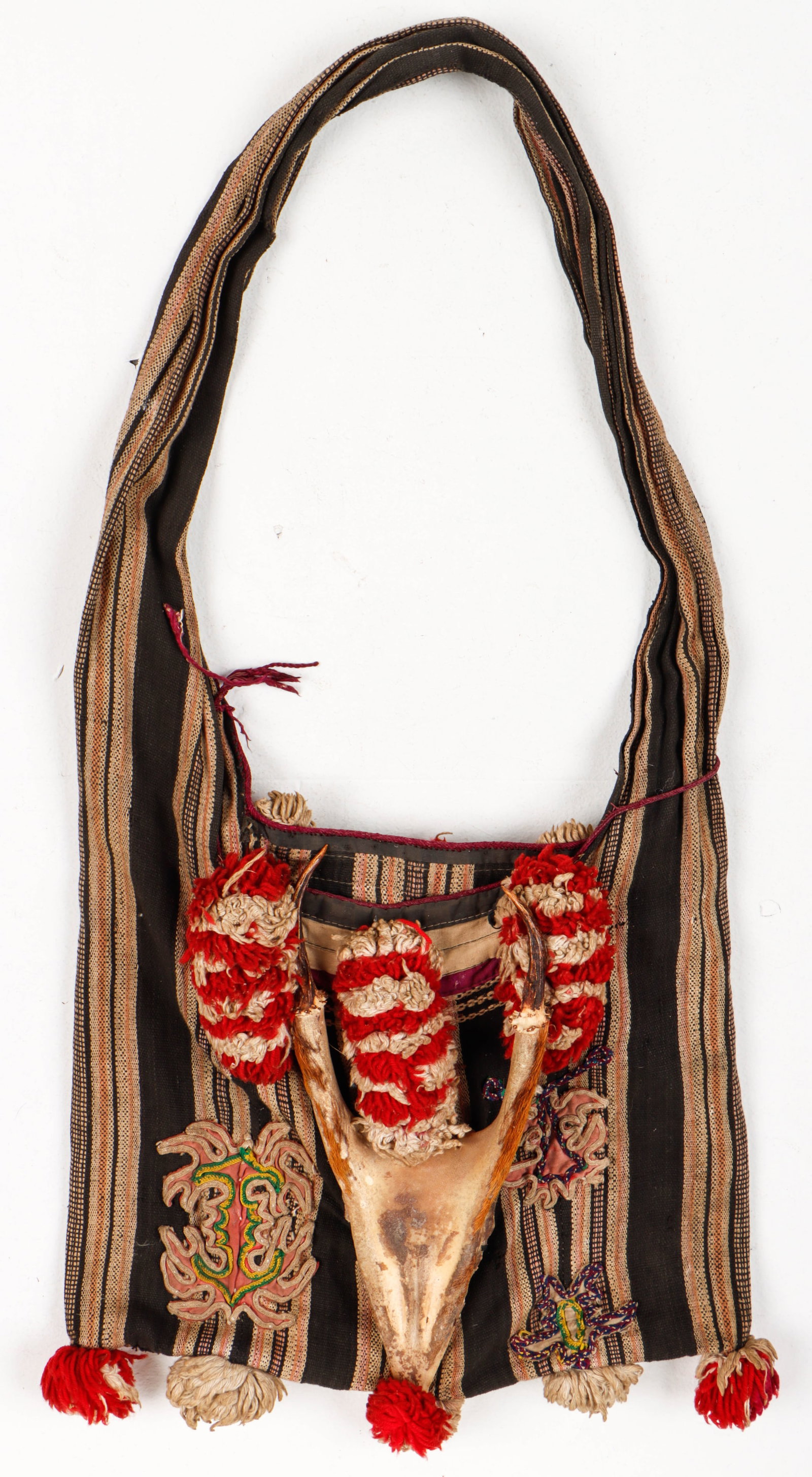 Yao Hill Tribe Hunting Bag, Southern China: Yao Hill Tribe Hunting Bag, Southern China. Striped woven cloth with applique embroidery, red and white pom-poms and a horned animal skull fragment adornment. Size: 26'' x 13'' (66 x 33 cm).