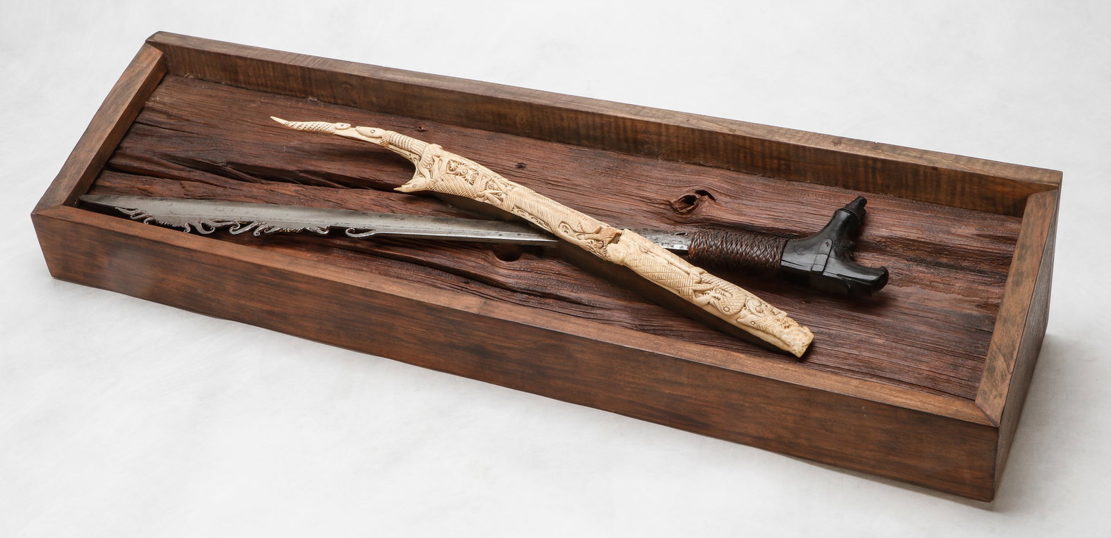 Borneo Dayak Parang Ilang Sword: Borneo Dayak Parang Ilang Sword with remnants of bone scabbard. Mounted on display box. Size: 8" x 31" x 5.5", 20 x 79 x 14 cm (display), 21", 53 cm (blade). Provenance: DeHoogh Gallery, Philadelphia.