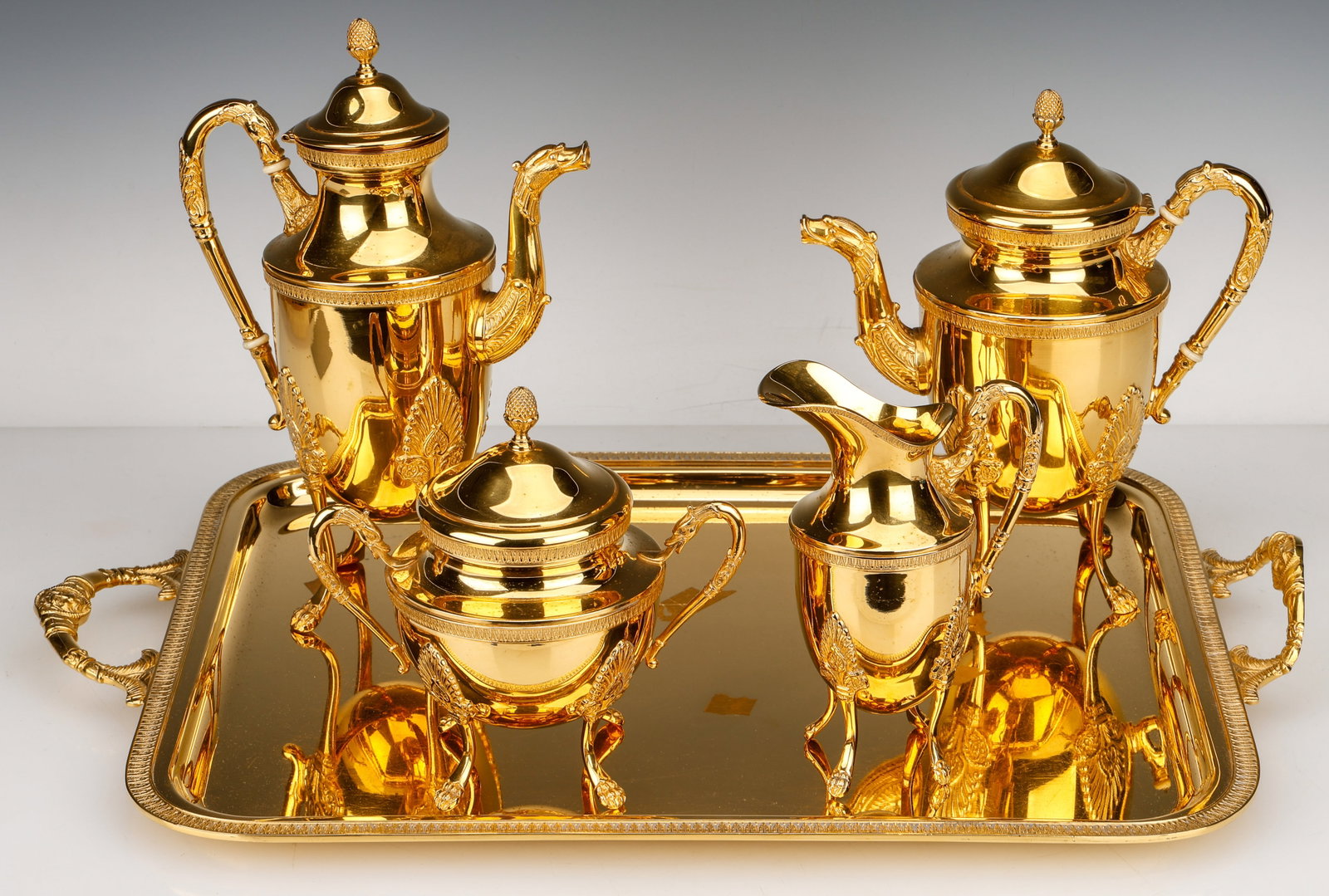 French Empire Style Gold Tone 4-Piece Tea Service And Tray, 20th C.: French Empire Style Gold Tone 4-Piece Tea Service And Tray, 20th C. In the manner of Cristofle's Malmaison Empire services. Size: Tray: 22'' x 14.5'' (56 x 37 cm). Heights ranging from 7"11" (18- 28 c