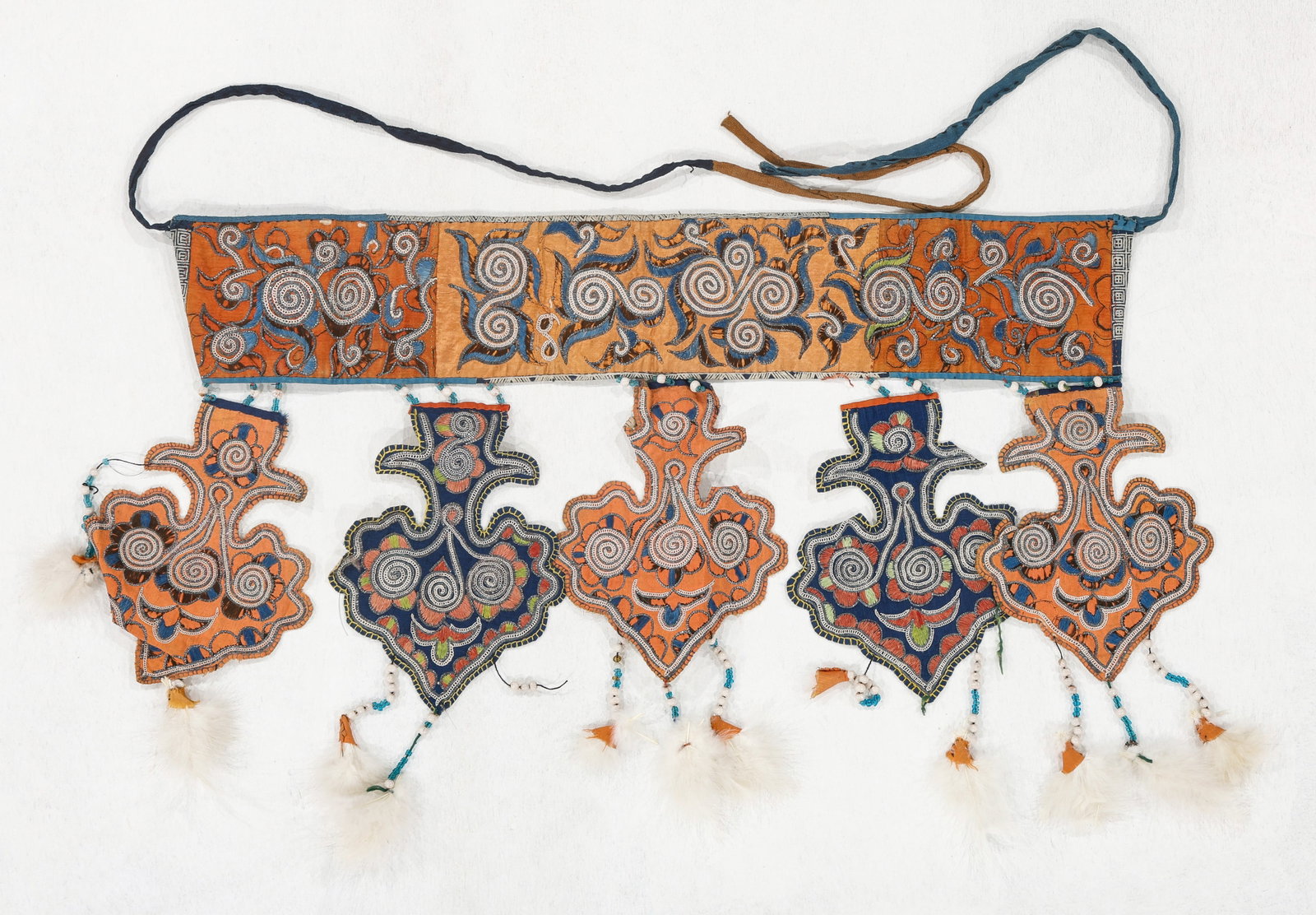 Miao Apron with Cloud-Form Pendants, Early/Mid 20th C.: Miao Apron with Cloud-Form Pendants, Early/Mid 20th C. Apron made of a wide band of embroidered and foil couched satin, edged with wax resist cotton. Cotton fabric tie ends. Five attached cloth pendan