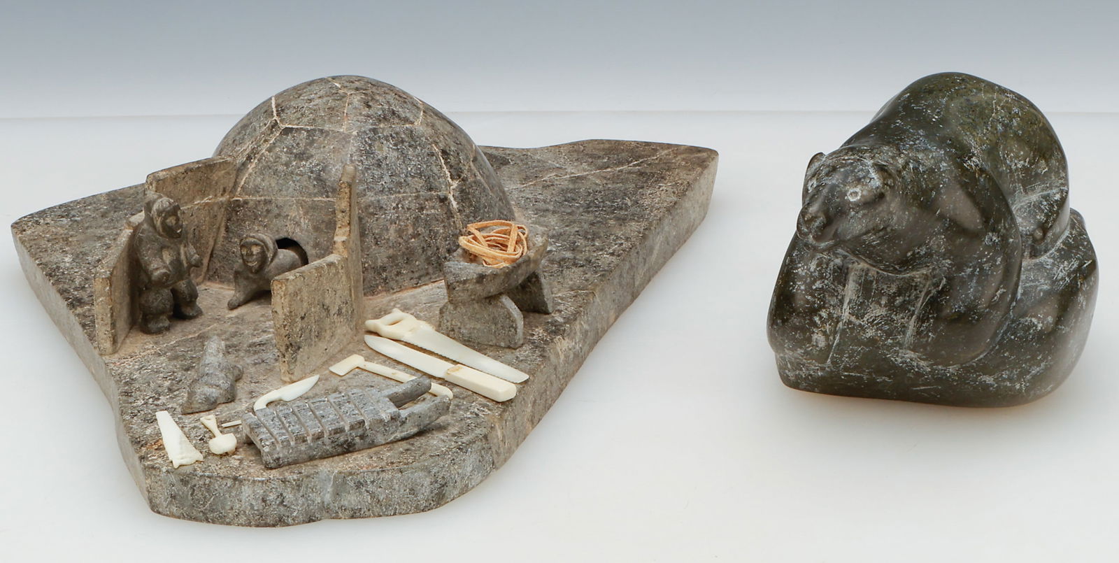 2 Inuit Carved Stone Sculptures And Miniature Walrus Tusk Tools: 2 Inuit Carved Stone Sculptures And Miniature Walrus Tusk tools. 1) Euguen Naujat, Igloo Camp, soapstone, caribou antler. Size: 3'' x 10.5'' x 8'' (8 x 27 x 20 cm). 2) Johnny Iqulik (Iquliq) (1966-199