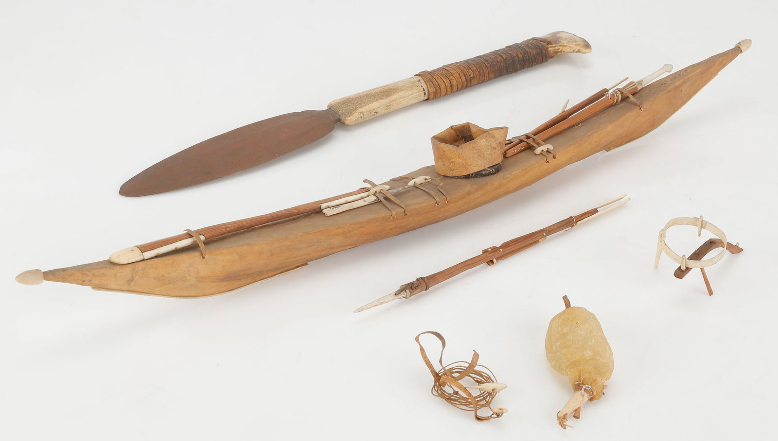 Antique Inuit Seal Skin Kayak Model, C. 1920 And An Antique Copper Knife, C. 1820-1850: Antique Inuit Model of a Kayak And Equipment, C.1920. Wood, baleen, ivory, seal bladder, seal skin, sinew. Together with an antique knife, C. 1820-1850, copper, caribou bone. Sizes Ranging From: 4.5''