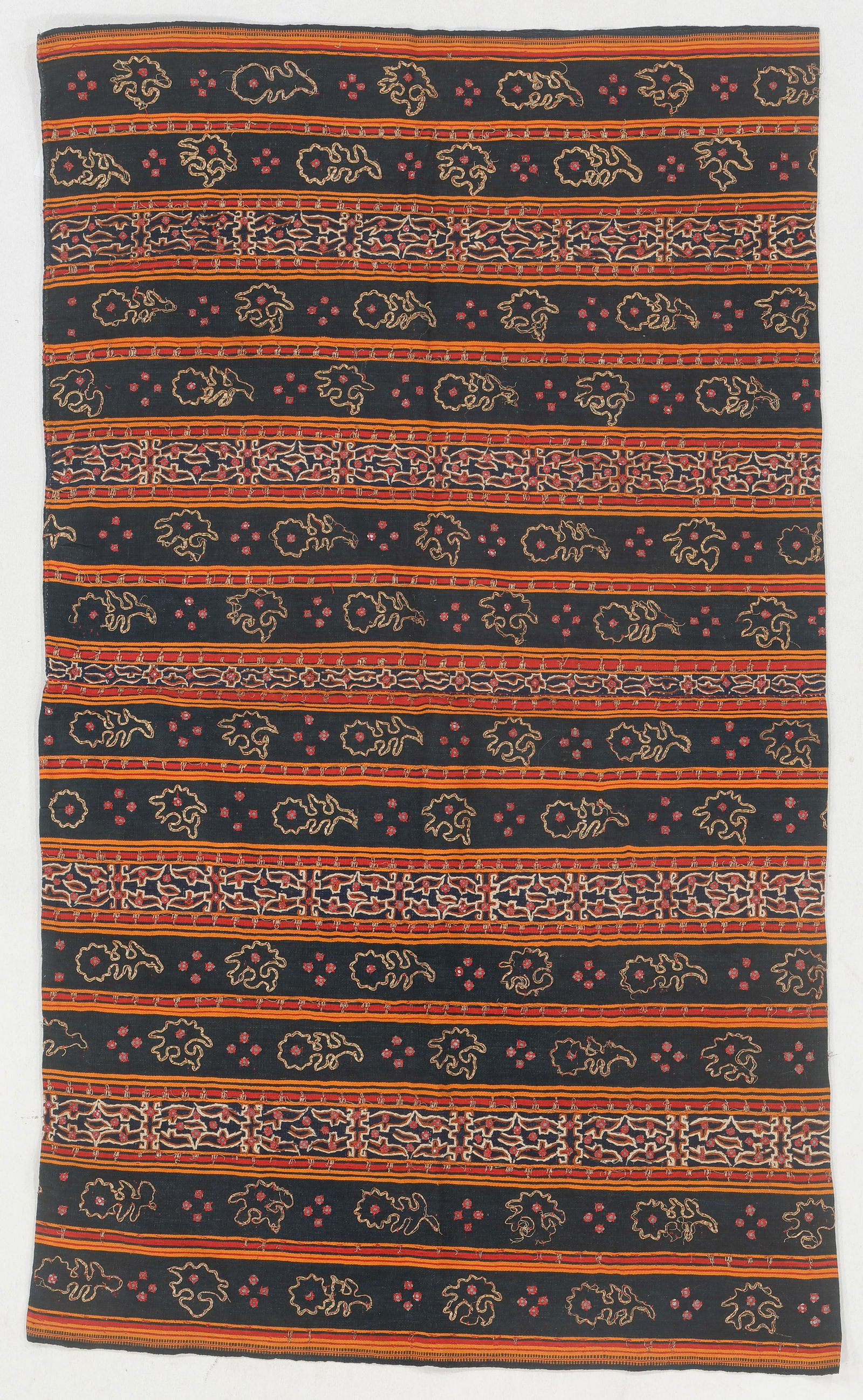 Lampung Tapis Tube Skirt, South Sumatra, Indonesia: Lampung Tapis Tube Skirt, South Sumatra, Indonesia. Cotton with couching, mirror pieces, and metallic thread with orange and red stripes on a navy blue ground. 2'1'' x 3'8'' (64 x 112 cm). Provenance: