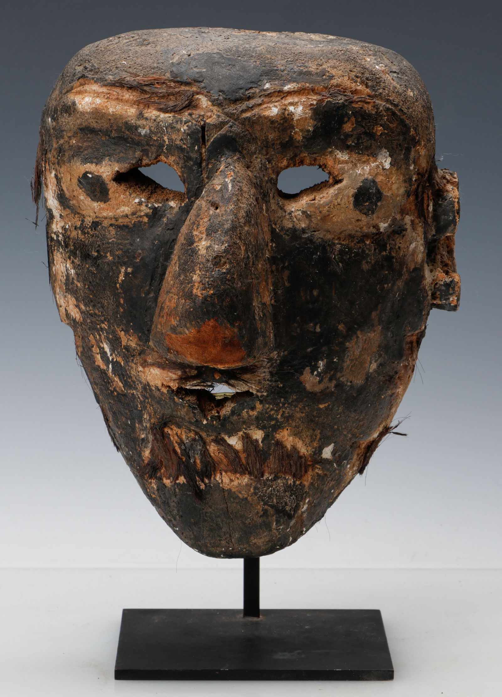 Mexican Carved and Painted Wood Character Mask, Michoacan State: Mexican Carved and Painted Wood Character Mask, Michoacan State. Wood, pigment, and hair. On stand. Size: 10'' x 8.5'' x 6.5'' (25 x 22 x 17 cm); Height on stand: 14'' (36 cm). Provenance: Estate of N