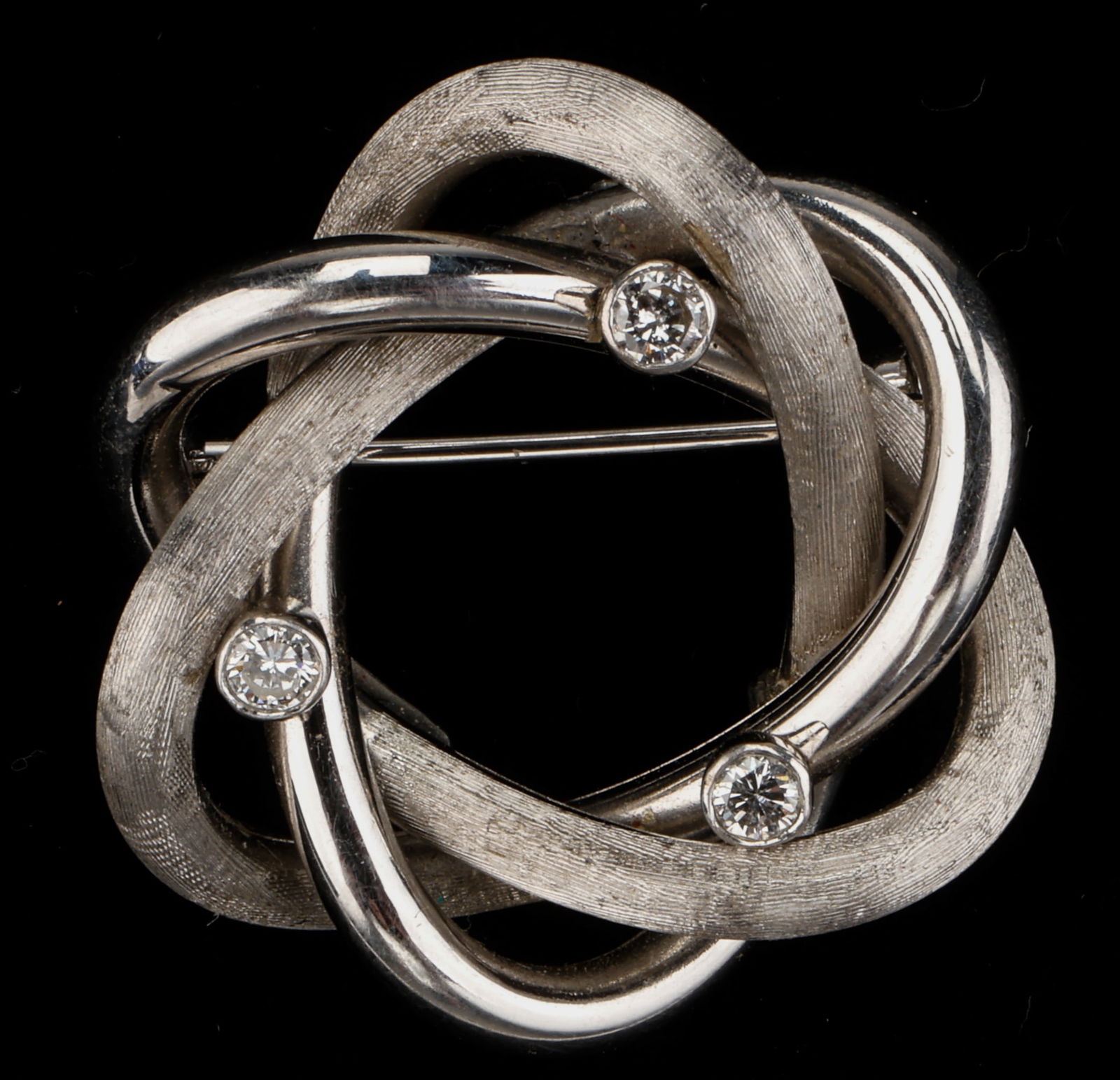 .750 White Gold And Diamond Brooch: .750 White Gold And Diamond Brooch. 3 diamonds. Marked: .750. Diameter: 1" (3 cm). Gemstones have not been weighed, or graded for color and clarity. 4.2 pennyweight.