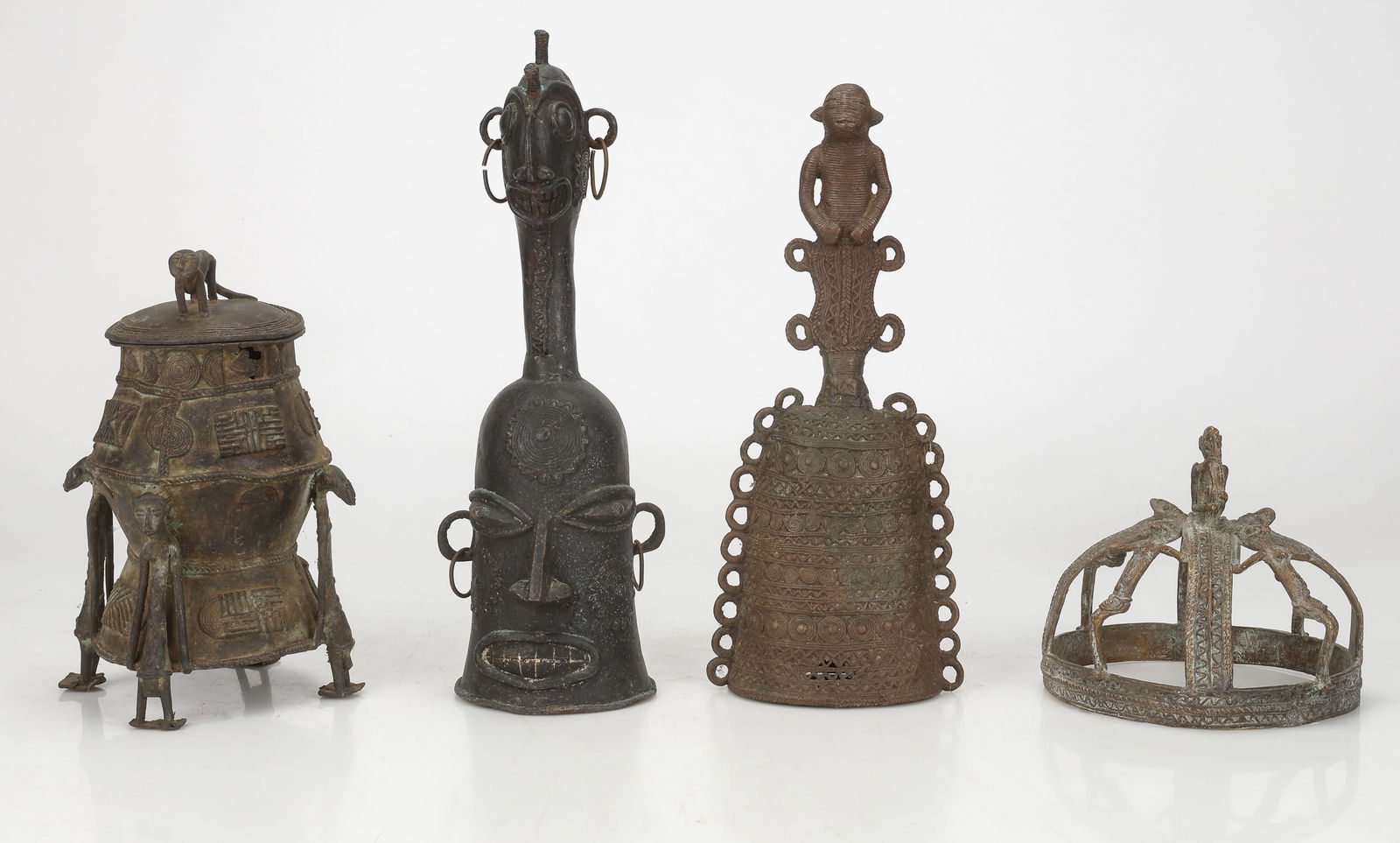 4 Benin And Dogon Bronze Items, H: 7"-16": 4 Benin Bronze Items including a 1800s Dogon Tribe Crown, An African Bronze Bell, A Helmet Bronze Bell, And a Lidded Vessel. Sizes From: 7'' x 8'' x 8'' (18 x 20 x 20 cm); To: 16'' x 6'' x 5'' (41 x 1