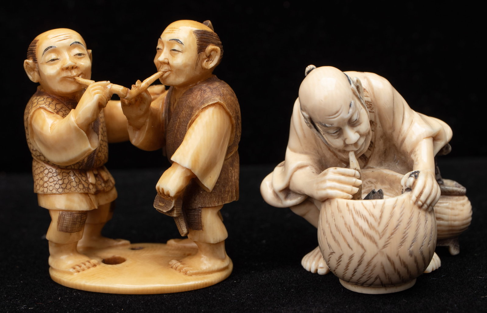 2 Antique Signed Japanese Netsukes, Men Lighting And Smoking Pipes: 2 Antique Signed Japanese Netsukes. One with a Pair of Travelers, one helping to light the other's pipe; the second showing an old man leaning down and lighting his pipe from the hot coals of a brazie