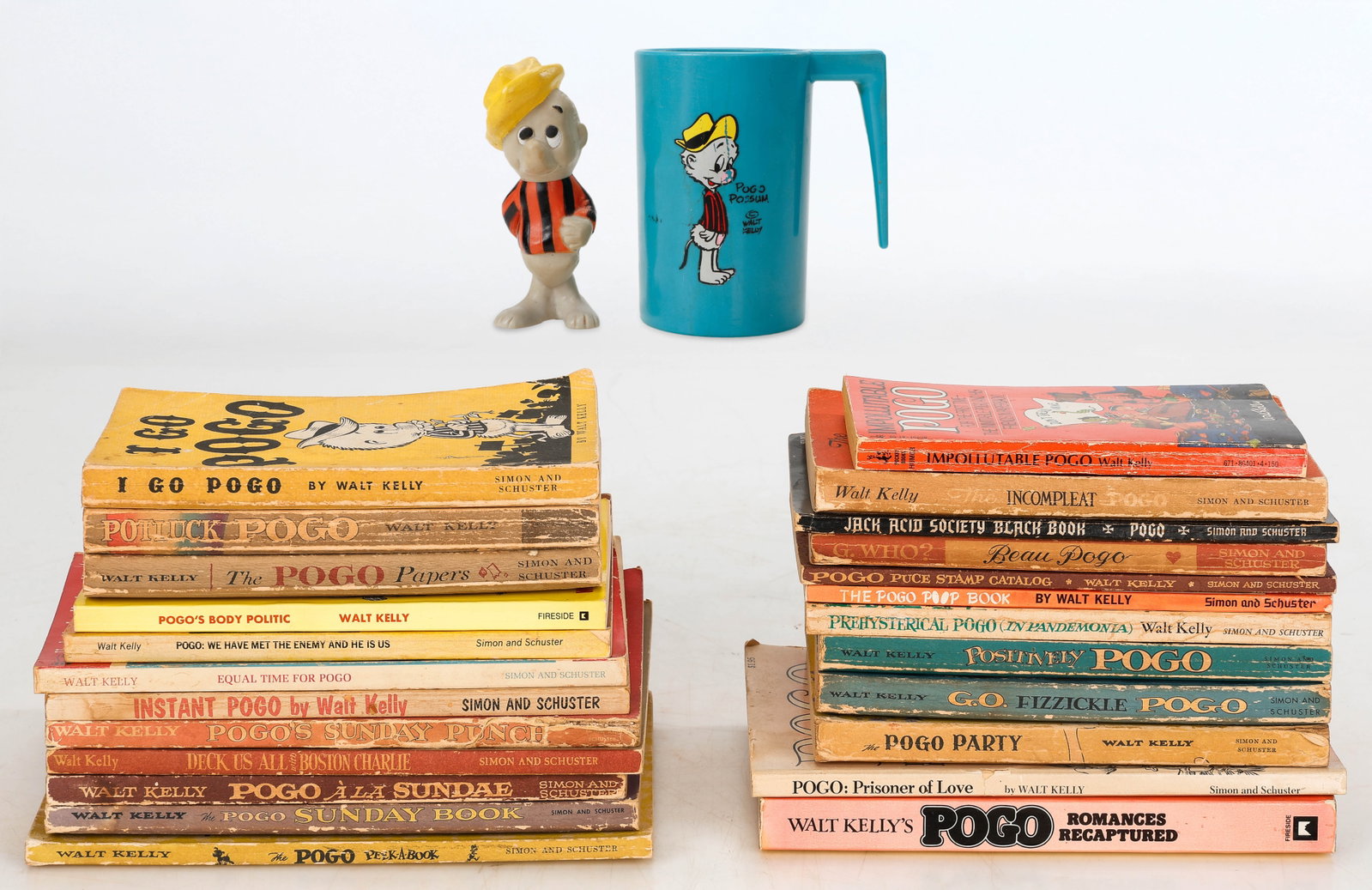 Walt Kelly Collection of Books And Memorabilia: Walt Kelly Collection of Books And Memorabilia. Including: Walt Kelly Pogo Possum Plastic Mug And Figure, circa 1970's. Sizes: 1) 4'' x 1.5'' x 1.5'' (10 x 4 x 4 cm) (figure); 2) 4'' x 3.5'' x 2.5'' (