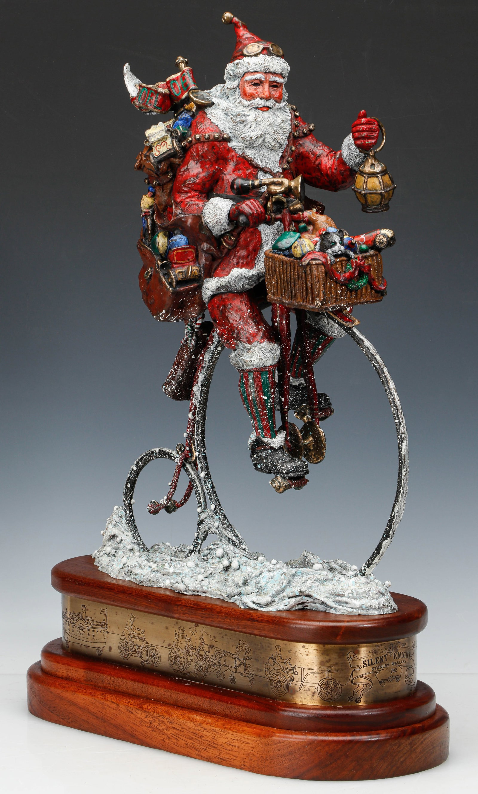 Stanley Wanlass (American, b.1941) "Silent Knight" Santa Claus Cold Painted Bronze, H: 26": Stanley Wanlass (American, b.1941) "Silent Knight" Cold Painted Bronze, 1992. Signed and numbered: "S. Wanlass 29/92." Christmas Santa Claus laden with gifts riding through the snow on a vintage "Penn