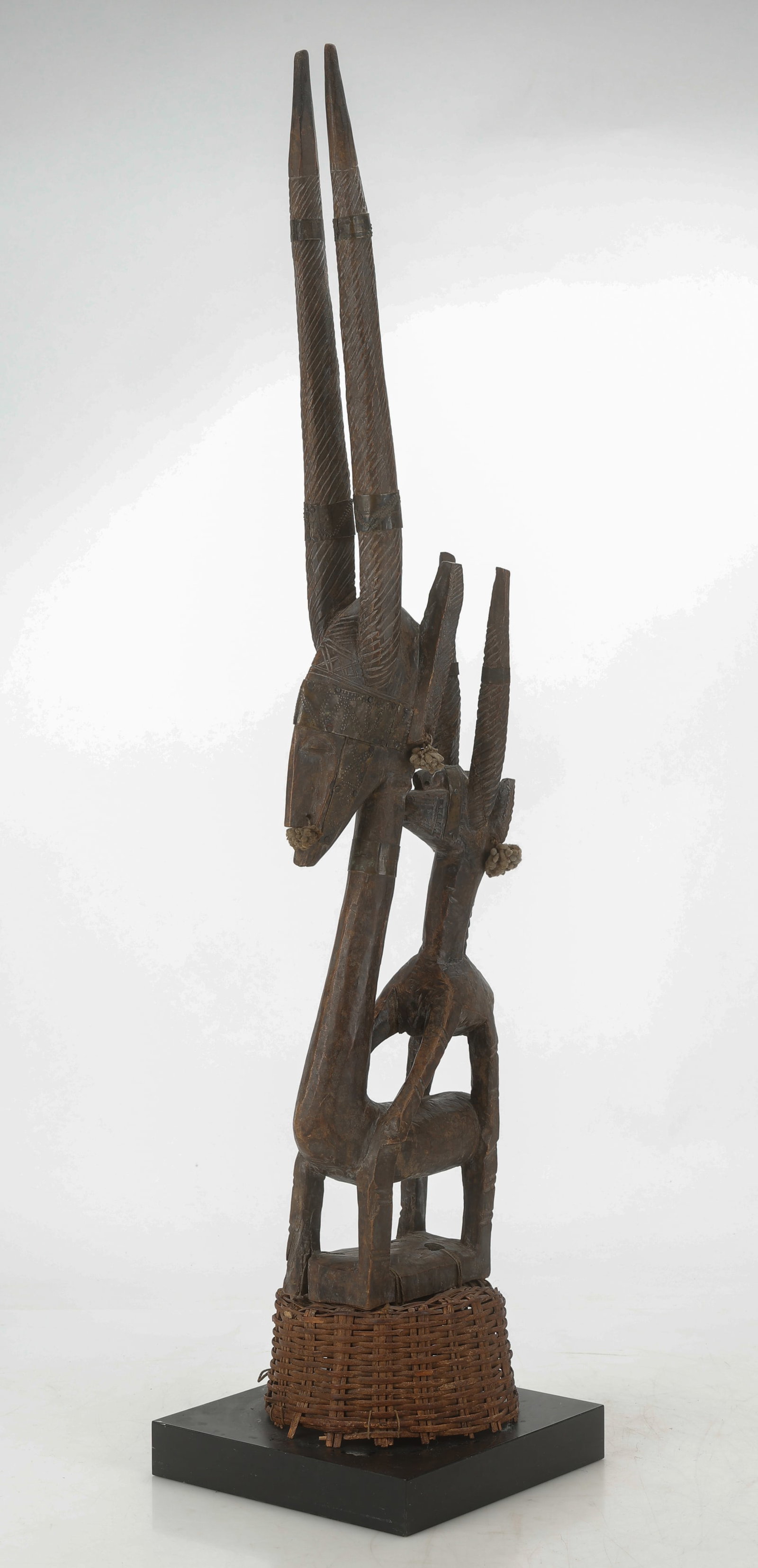 African Bamana Chi Wara Headdress, Mali: African Bamana Chi Wara Headdress, Mali. With original basketry headdress. Carved wood and plant fiber. On stand. Size: 37.5'' x 9'' x 6.5'' (95 x 23 x 17 cm), Height On Stand: 39" (99 cm). Provenance