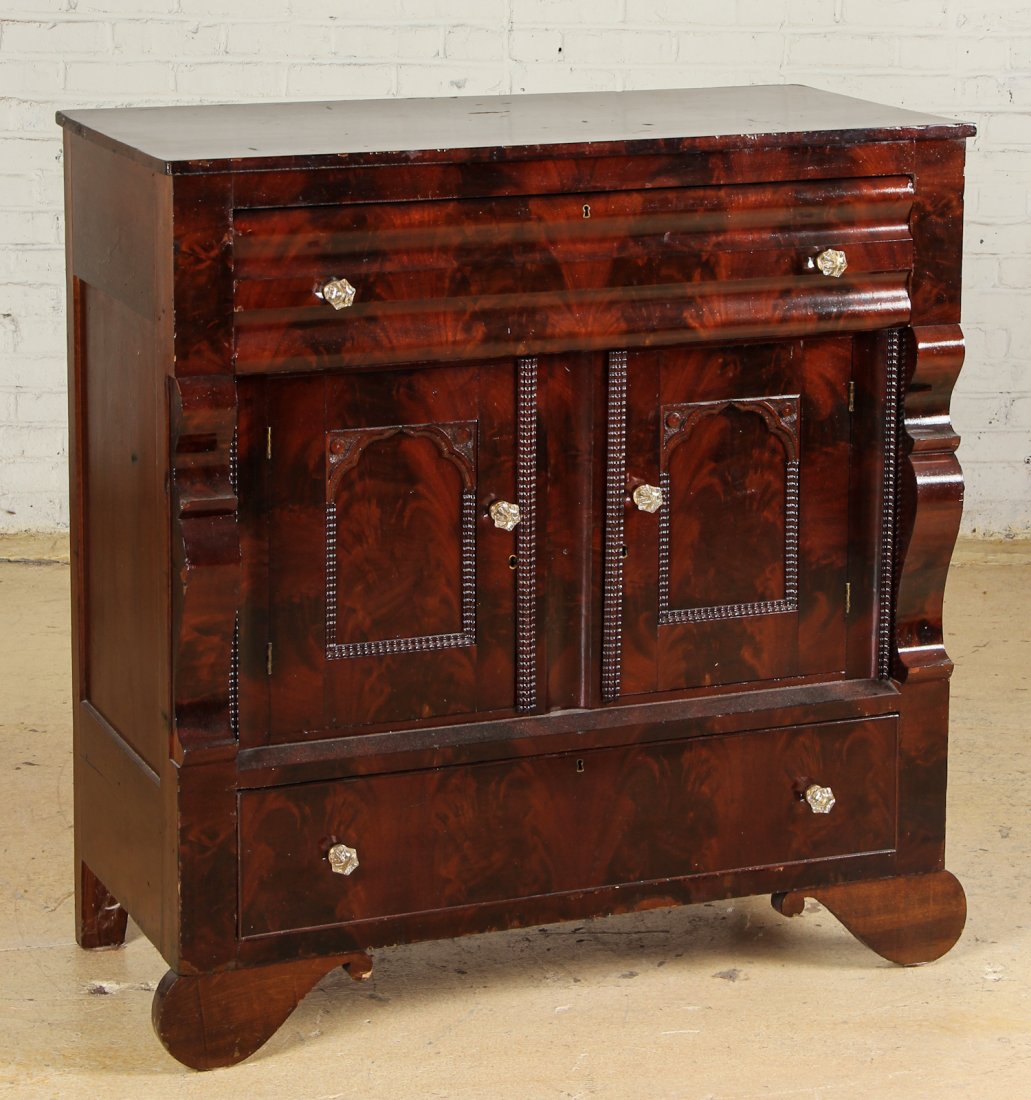 Empire Mahogany Sideboard: Empire Mahogany Sideboard. Featuring jeweled knobs, serpentine columns, and shaped feet. With 2 doors between an upper flatware drawer and lower linens drawer. Size: 45" x 42.5" x 21.5", (114 x 77 x 5
