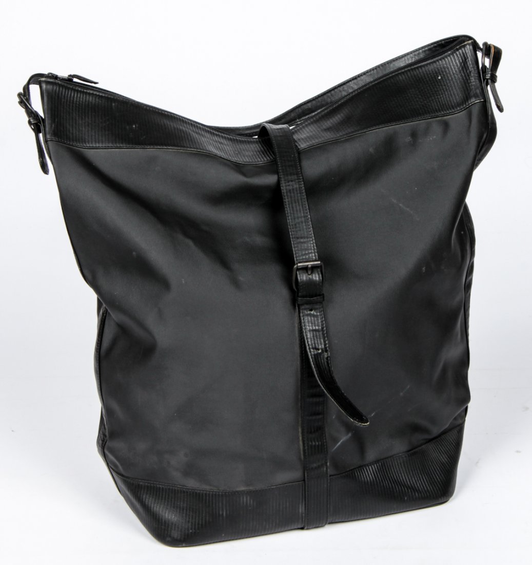 Rare Versace Black Leather Travel Bag: Rare Versace Black Leather Travel Bag. A flat bottom tote with buckled roll top and shoulder strap. Labeled Gianni Versace. Size: 20" x 21" x 10" (51 x 53 x 25 cm).