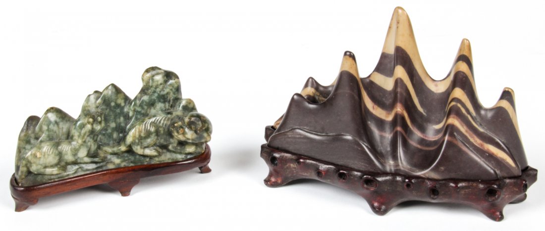 2 Chinese Stone Carvings, Qing D: 2 Chinese Stone Carvings, Qing D: Comprised of a Chinese steatite mountain form brush rest and soapstone Fu lion brush rest on wooden stand. Largest Size: 4" x 5.5" x 2.25" (10 x 14 x 6 cm). Provenanc