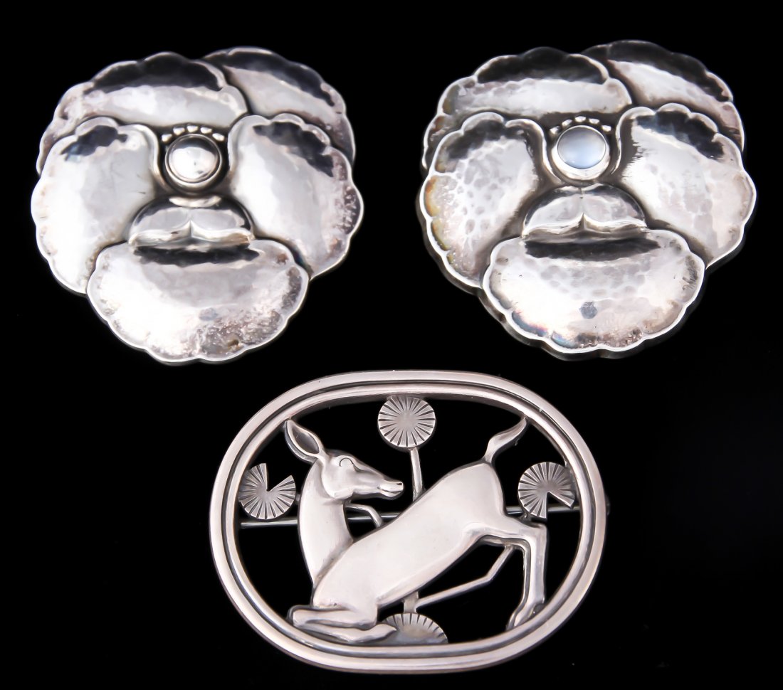 3 Georg Jensen Art Deco Style Brooches: 3 Georg Jensen Art Deco Style Brooches. Consisting of 2 #113 Pansies and a #256 Kneeling Deer Brooch. Total weight: 1.3 ozt. Largest Size: 1.5"L x 1.5"W, 4 x 4 cm.
