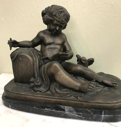 Bronze Statue of Boy Reading with Bird: Bronze statue of a boy reading notes/journal with a bird. Has good details, in good condition. Mounted on a black marble base. Measures approx. 15"H x 20"W x 11"D.