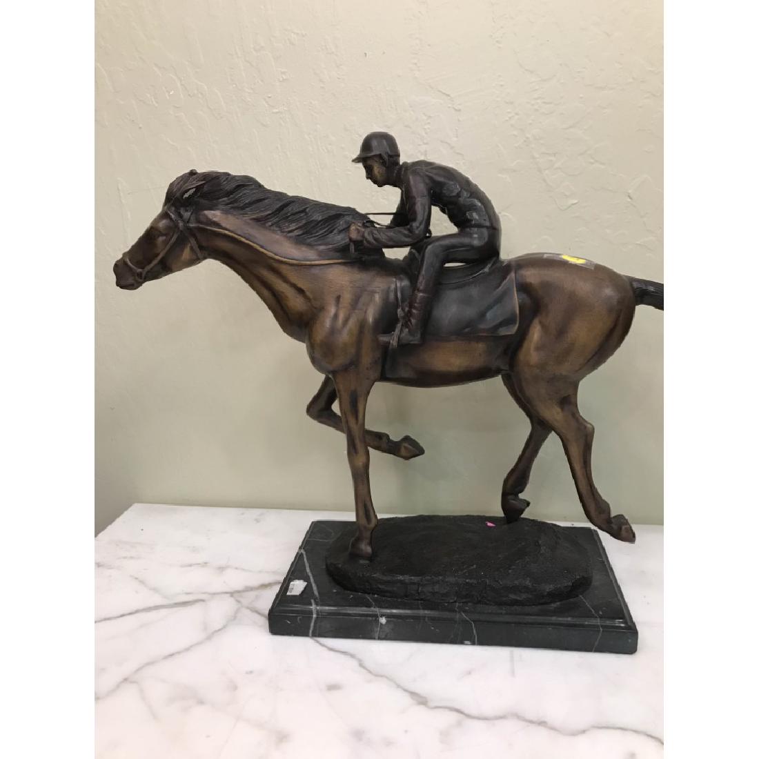 Bronze Statue of Jockey on Horse Racing: Bronze statue of a jockey on horse racing with good details. Mounted on a black marble base. In good condition. Measures approx. 16"H x 23"W x 6.5"D.