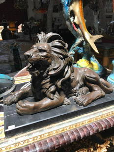 Bronze Lion Statue on Marble Stand: Spectacular bronze statue of a lion sitting. Mounted on a solid black marble base. Good details throughout. In good condition. Measures approx. 16"H x 26"W x 13"D.