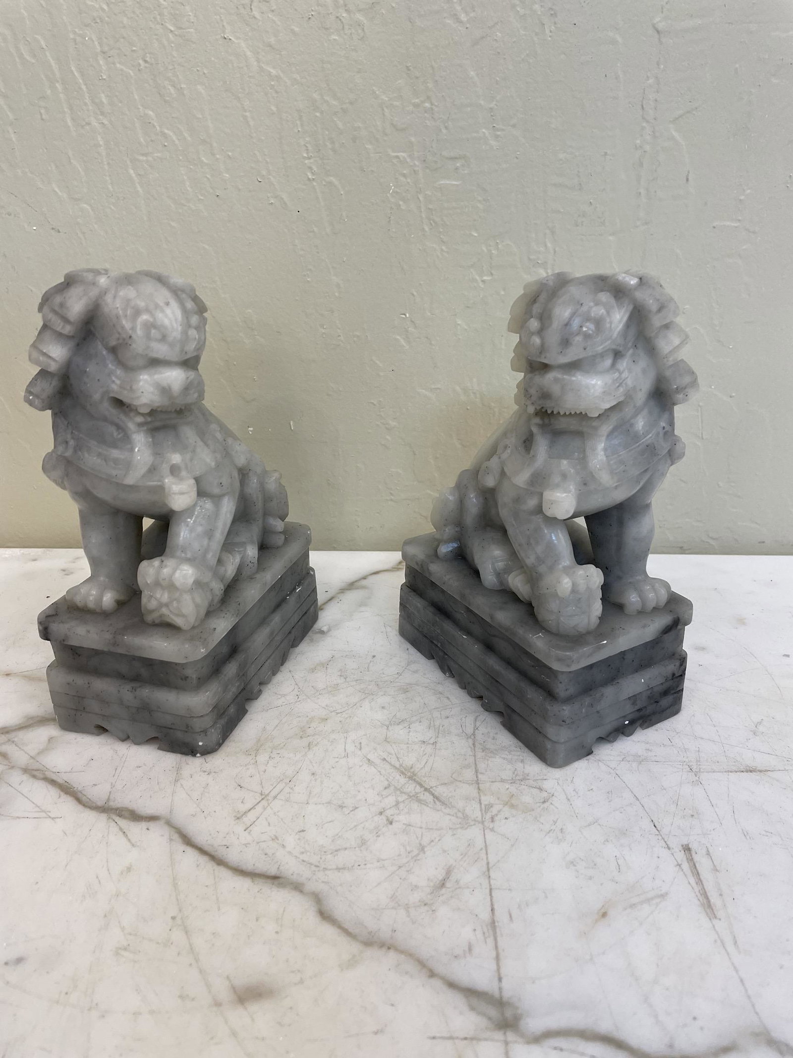 Pair of Jade Foo Lion Statue: Pair of hand-carved foo lion statues carved out of jade. One female and one male lion carved with good detail. Both in good condition. Each measures approx. 7"H x 3"W x 4.5"D. From a local, private es