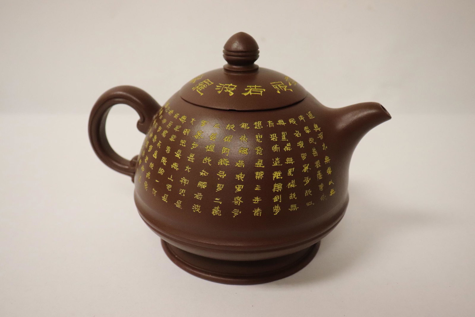 A Yixing teapot with calligraphy: A Yixing teapot with calligraphy, cover inside rim chip, 5"Hx6.75"x4.9"