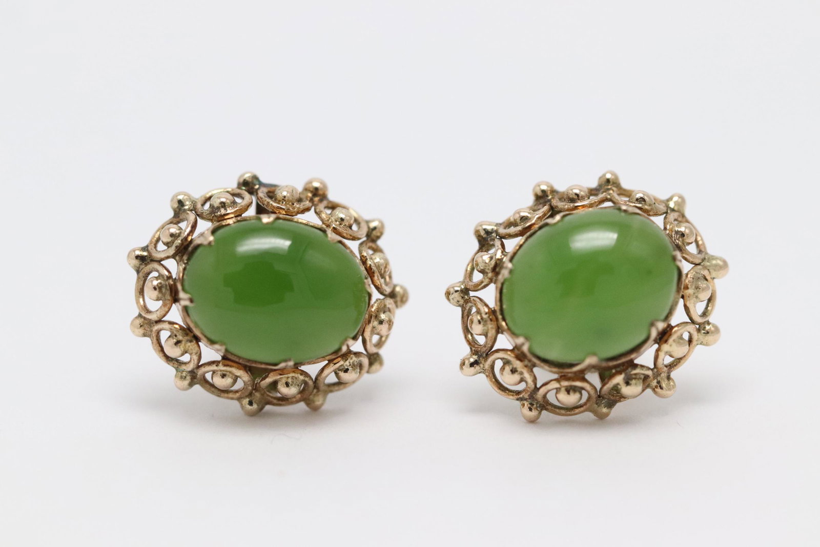 Pair fancy 14K Y/G jadeite earrings: Pair fancy 14K Y/G earrings, each set with a jadeite cabochon measures approx. 10x8mm