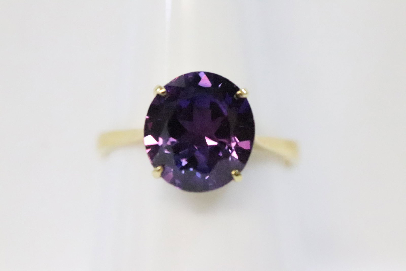 14K Y/G ring w/ a brilliant purple color stone: 14K Y/G ring, center a brilliant purple color stone, possible a synthetic alexandra measure approx. 10.5x9.5mm, wt. 3.5gm, size 6.5