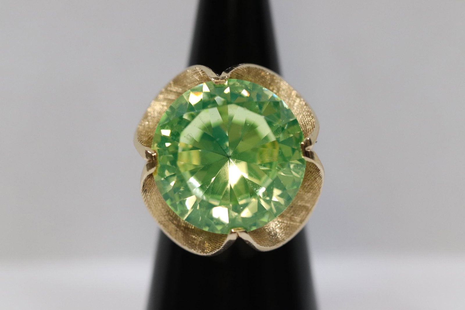 A 14K Y/G ring with a large light green stone: A 14K Y/G ring, center a large light green stone, possible peridot, wt. 15.5gm, size 6