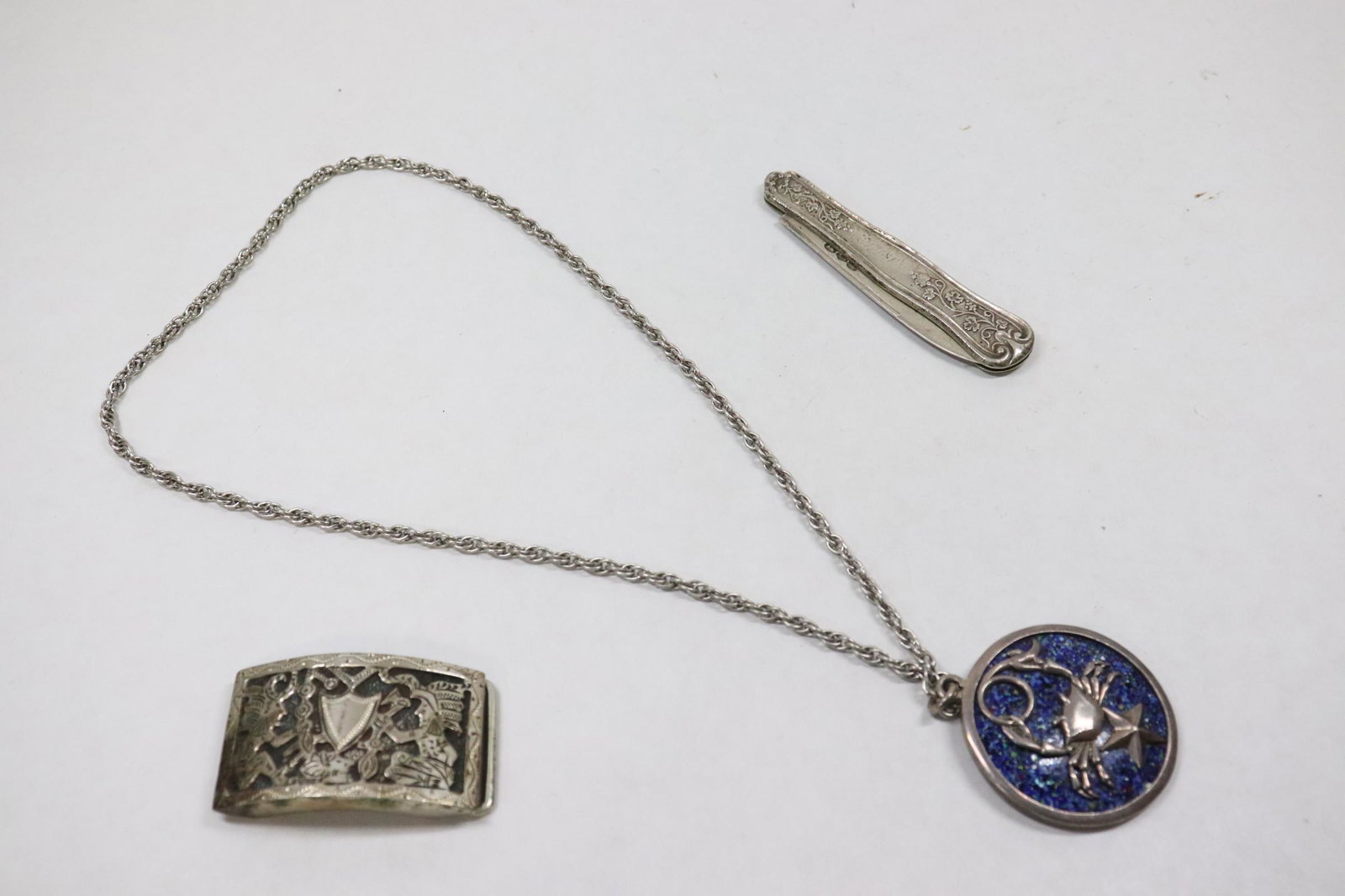3 pieces: 3 pieces; sterling pendant (1.68"dia) with necklace by Margot of Taxco, a belt buckle (1.2"x2") and a sterling knife (3.2"L), wt. 112gm